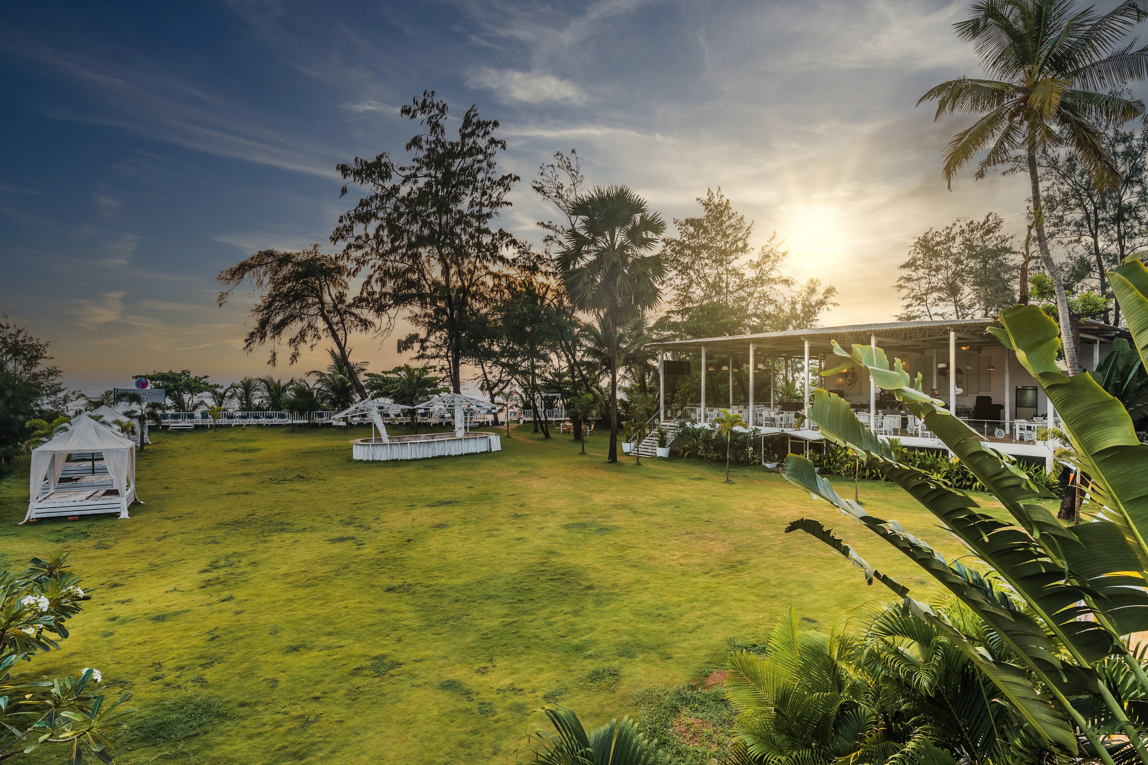 A spacious outdoor area with a grassy lawn, a white gazebo, and a covered seating area with tables and chairs.
