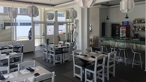 Een modern restaurant met witte meubels, hangende吊り下げライト en een bar voorzien van een Coca-Cola koelkast.