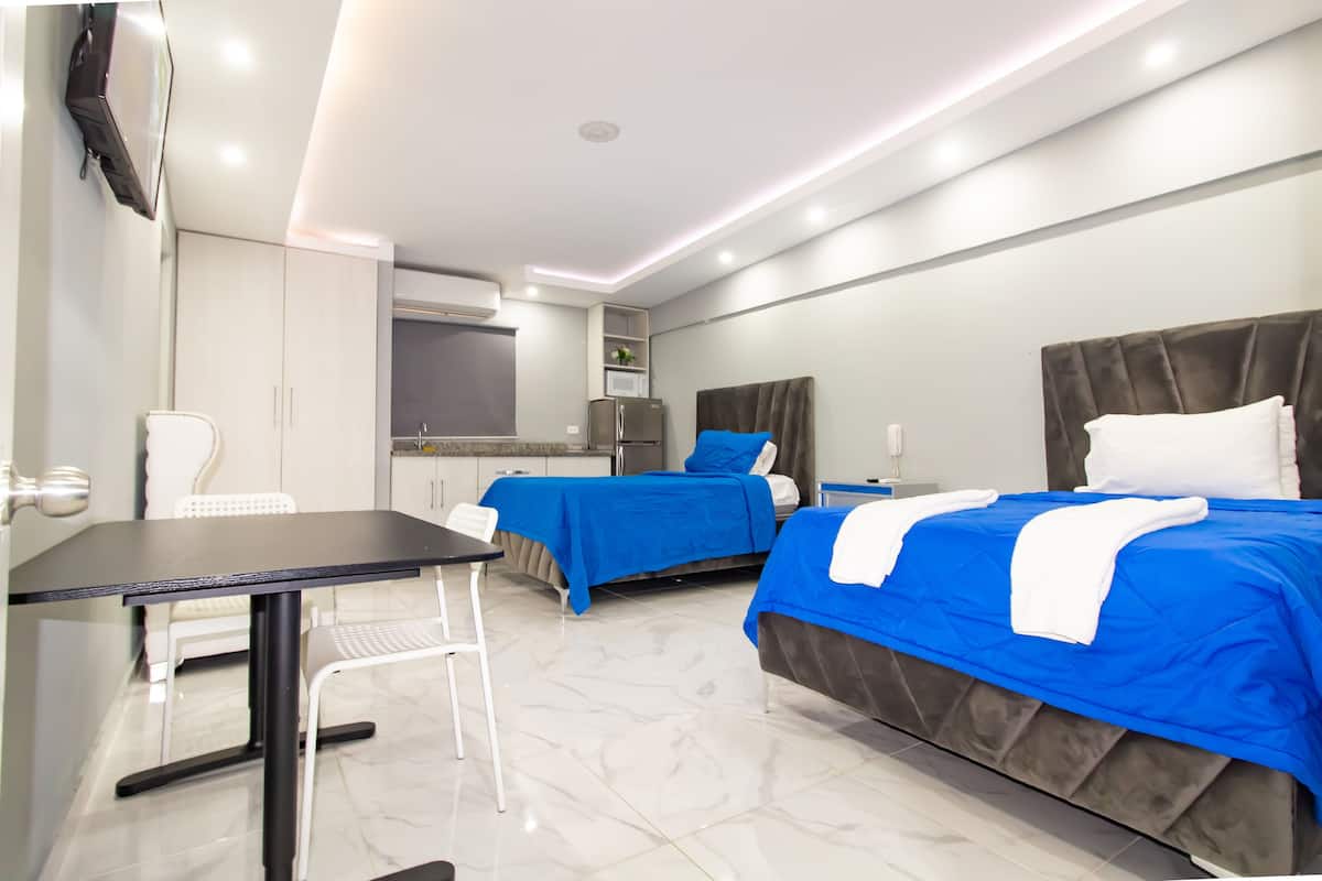 A hotel room with two beds, a desk, a chair, a TV, a microwave, and a wardrobe.