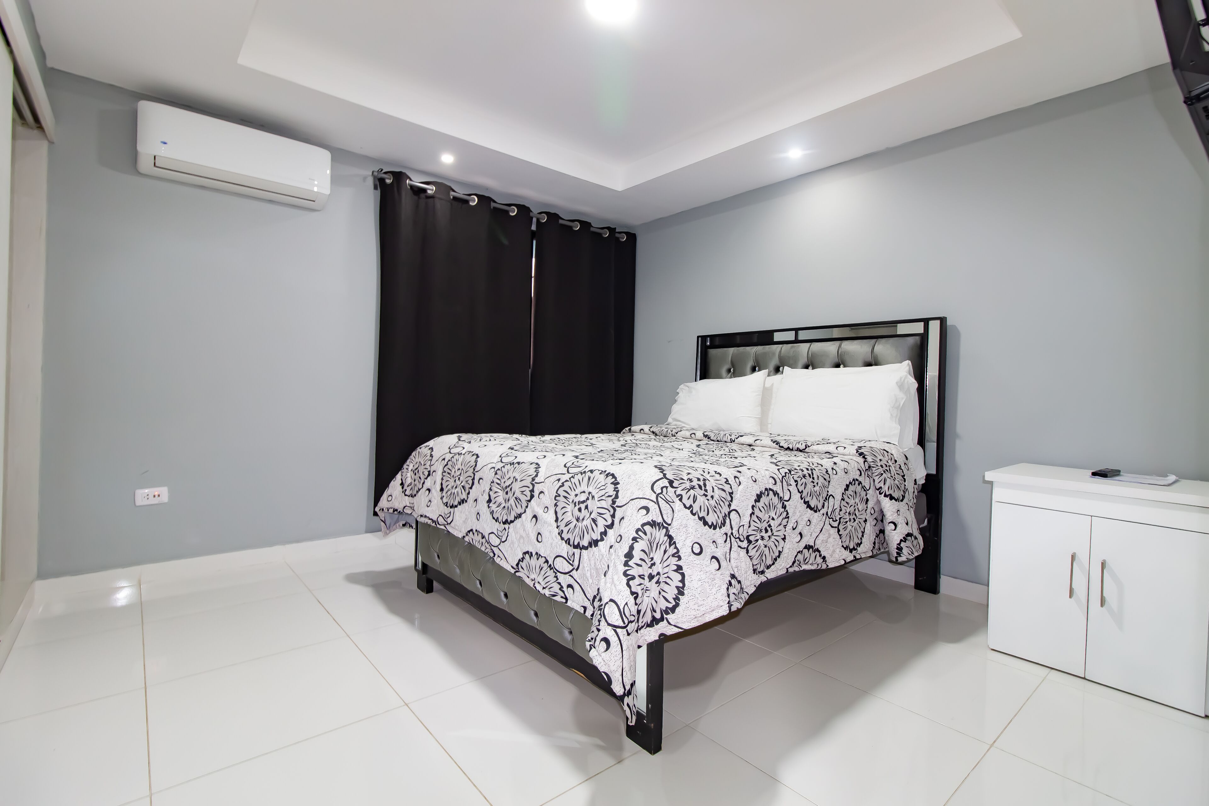 A bedroom with a bed, a white cabinet, and an air conditioning unit.