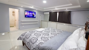 Een moderne slaapkamer met een groot bed, een aan de muur bevestigde televisie en een inloopkast.
