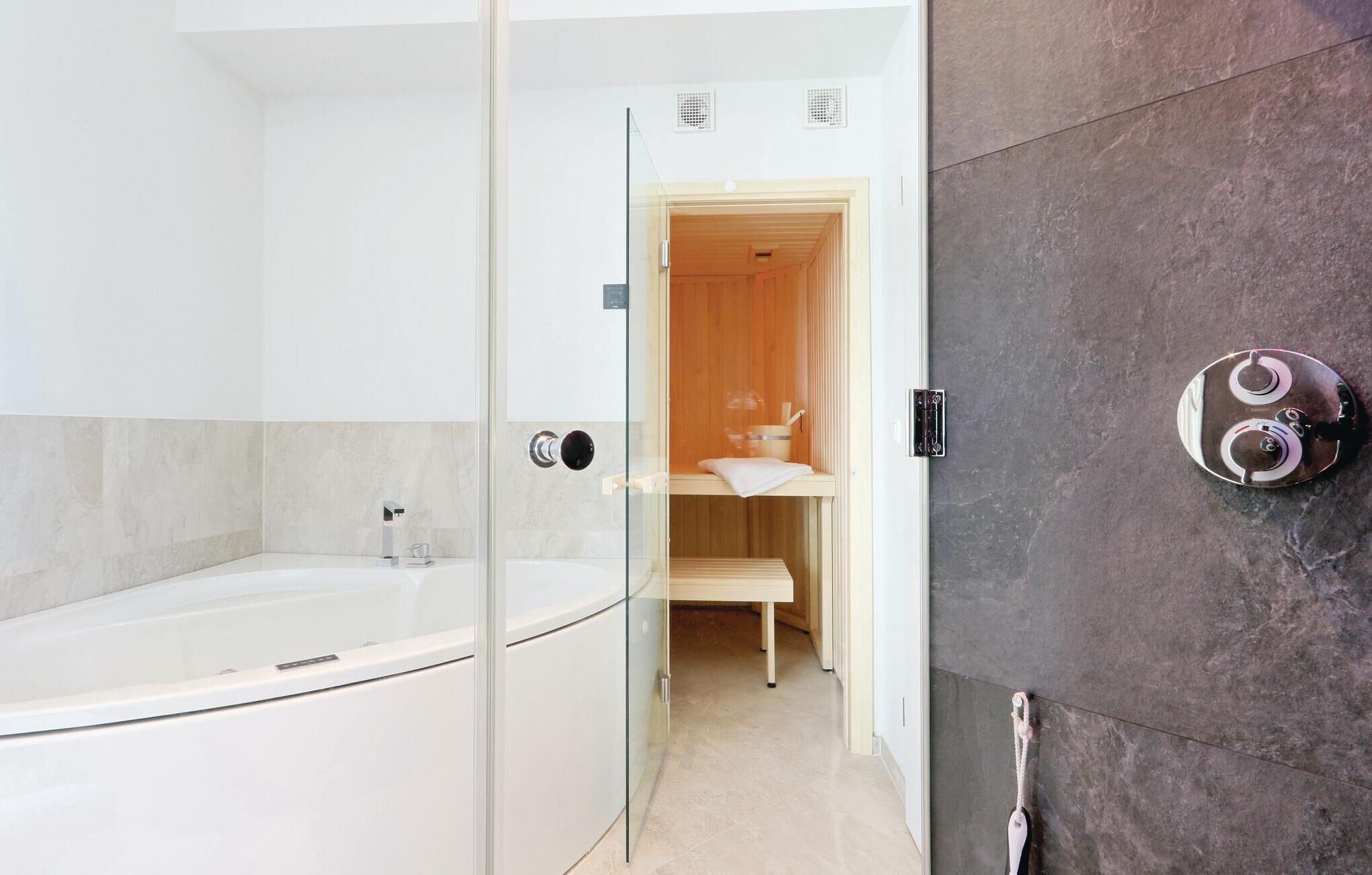 A modern bathroom with a glass-enclosed shower, a white bathtub, and a wooden vanity with a towel rack.