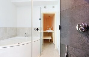 A modern bathroom with a glass-enclosed shower, a white bathtub, and a wooden vanity with a towel rack.