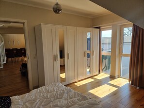 Un dormitorio con una cama grande, un armario y vistas al exterior a través de una puerta corredera.