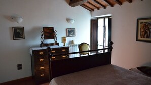Ein Schlafzimmer mit einem hölzernen Bett, einer Kommode mit Schubladen, einem Sessel und einem Fenster mit Blick.