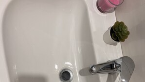 A white bathroom sink with a silver faucet, two small potted plants, and two pink glasses. - Hotel Oceania (Naples)