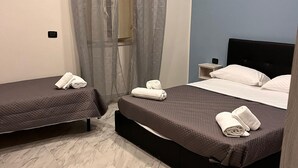 A hotel room with two beds, a bathroom, and a nightstand. - Hotel Oceania (Naples)