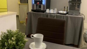 A hotel room with a coffee machine, a table with a cup and saucer, and a bowl of napkins. - Hotel Oceania (Naples)