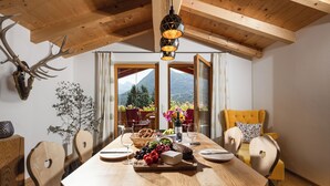 A wooden dining table with a variety of food items, surrounded by wooden chairs and a yellow sofa.