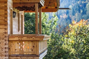 Une cabane en bois dotée d’un balcon, d’une lanterne et offrant une vue sur les arbres et les montagnes.