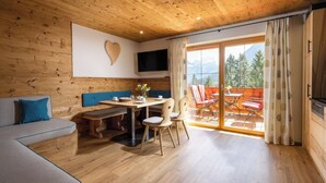 A wooden interior with a dining area, a sofa, and a TV mounted on the wall.