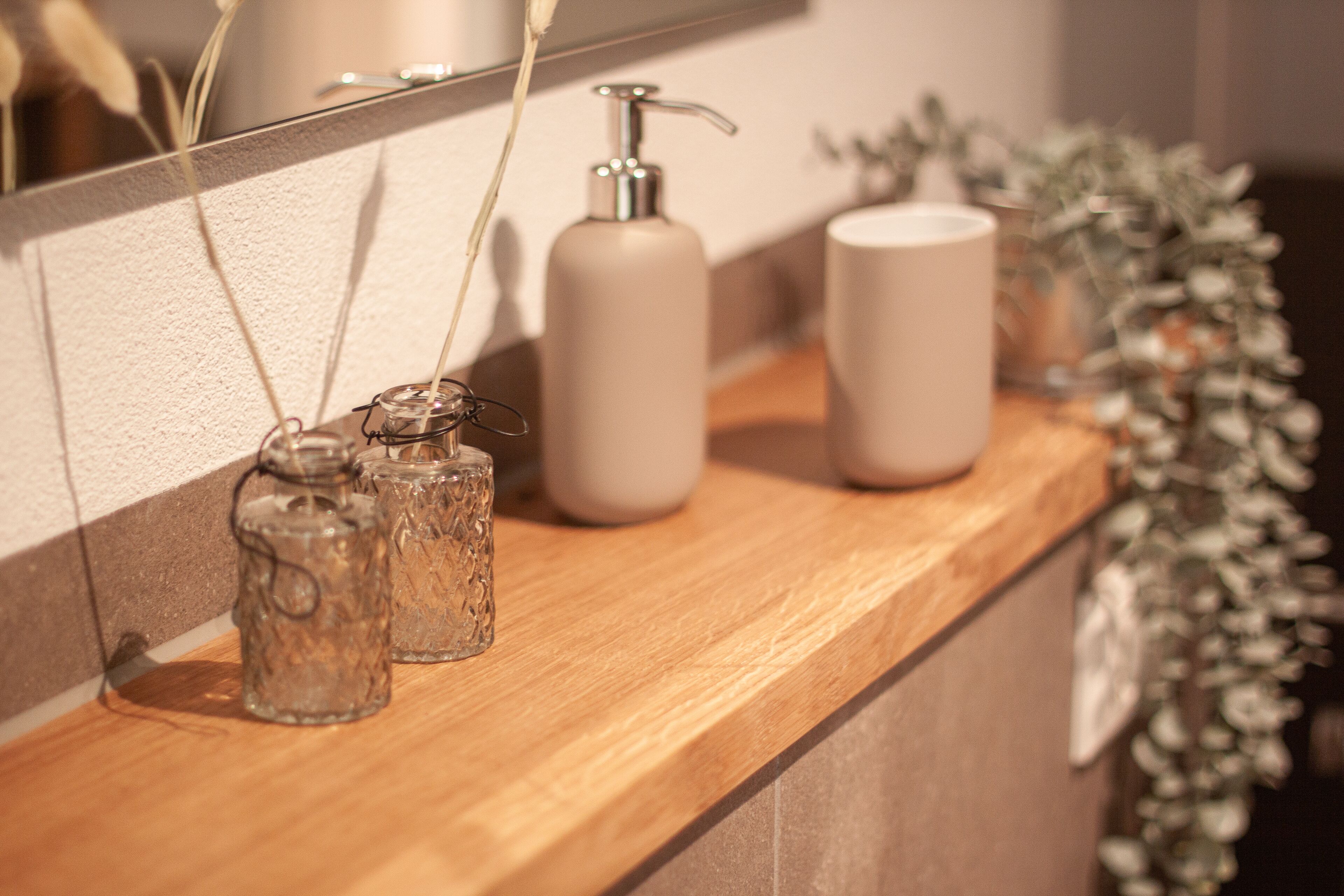 A bathroom vanity with a wooden countertop, a mirror, and a decorative plant.