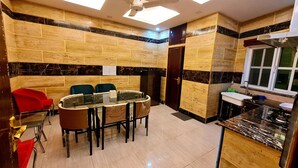 A compact kitchen with a dining area, featuring a built-in refrigerator, a sink, and a window. - Smart Apartments & Hotel (Lahore)