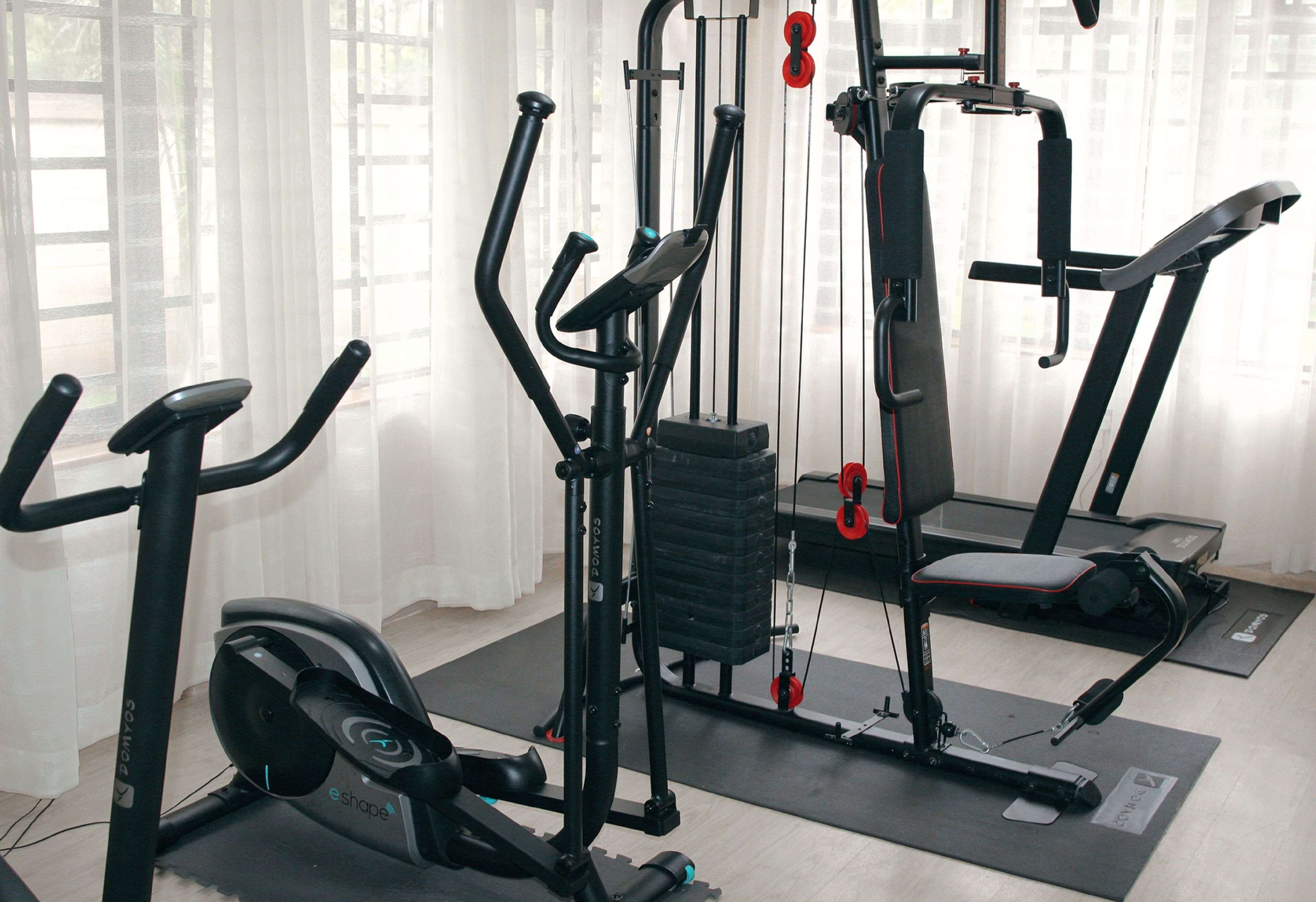 Un gimnasio con máquinas de cardio, equipo de entrenamiento de fuerza y una cinta de correr.
