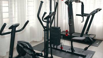 Un gimnasio con máquinas de cardio, equipo de entrenamiento de fuerza y una cinta de correr.