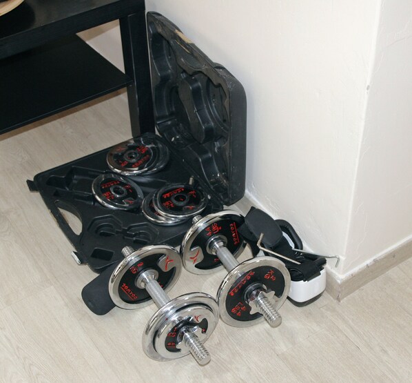 A set of dumbbells and a weight bench in a corner of a room.