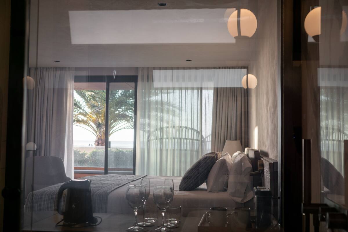 A hotel room with a bed, a sofa, a table with glasses, and a TV.