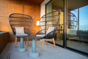 Un balcone con due sedie in vimini, un tavolino e una lampada.