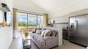 A modern apartment with a grey sofa, a dining table, and a kitchen area with a stainless steel refrigerator. - 3 bdrm/2 bath Villa w/pool, Azure Beach Residences (Oranjestad-West)