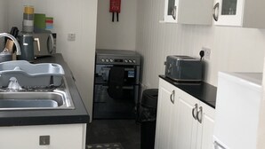 Eine kleine Küche mit weißen Schränken, einem Einbauofen, einem Spülbecken und einem Toaster.