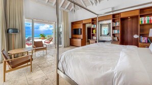 A spacious bedroom with a large bed, a wooden wardrobe, a television, and a balcony with a view of the ocean. - Villa Petite Plage 4 – Refined Beachfront Luxury in Grand Case, St. Martin (Grand Case)
