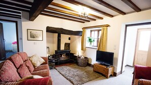 A cozy living room with a fireplace, a television, and a comfortable sofa. - Erw Rhys - sleeps 6 guests  in 3 bedrooms (Holyhead)