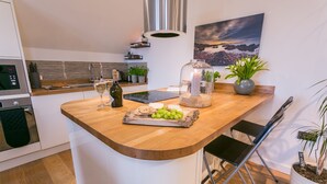 Eine moderne Küche mit einer Holzinsel, einem eingebauten Backofen und einer Edelstahl-Dunstabzugshaube.