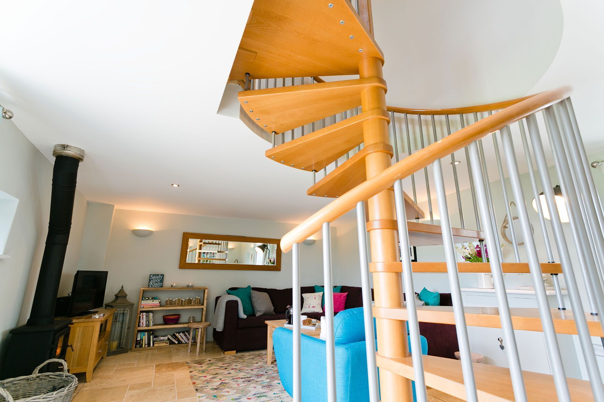 Una escalera de caracol con escalones de madera y barandillas metálicas que conduce a un piso superior.