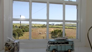 Ein Fensterblick auf eine ländliche Landschaft, ein kleines Modell-Wohnmobil und eine Papiertuchbox auf der Fensterbank.