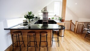 Eine moderne Küche mit einer Kochinsel, Barhocker und einer Holztreppe.