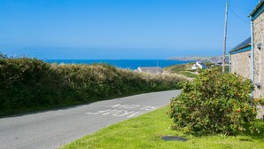 Eine Küstenstraße mit einem 'NO ENTRY'-Schild, einem Steinhaus und Blick aufs Meer.