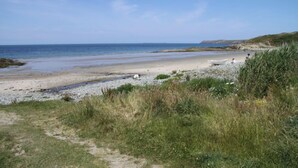 Une plage avec un chemin dégagé menant au rivage, une plage de sable et une mer calme.
