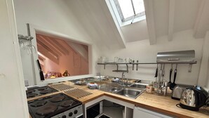 Une cuisine de taille réduite, équipée d’une cuisinière, d’un évier et d’une lucarne.