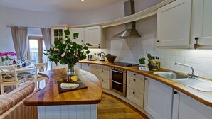 Une cuisine moderne avec des meubles blancs, un plan de travail en bois et un îlot central agrémenté d’un vase de fleurs.