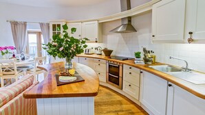Une cuisine moderne dotée d’un îlot central en bois, de meubles blancs et d’un four encastré.