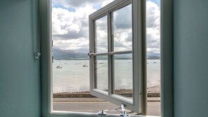 A window with a view of a calm body of water, boats, and distant mountains. - Pilot House -  a sea view that sleeps 8 guests  in 4 bedrooms (Beaumaris)