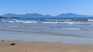 A beach with waves, sand, and distant mountains. - Pandy Aberffraw -  a dog that sleeps 4 guests  in 2 bedrooms (Ty Croes)