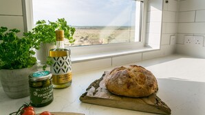 A kitchen counter with a loaf of bread, a bottle of olive oil, and a jar of pitted amfissa olives. - Pandy Aberffraw -  a dog that sleeps 4 guests  in 2 bedrooms (Ty Croes)
