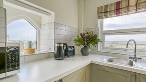 A kitchen with a microwave, a coffee maker, and a potted plant. - Pandy Aberffraw -  a dog that sleeps 4 guests  in 2 bedrooms (Ty Croes)