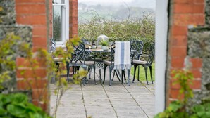 A patio with outdoor seating, a table with a glass enclosure, and a view of the countryside.