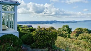 A conservatory with a view of a lake and distant hills. - Tan Y Bryn -  a sea view that sleeps 10 guests  in 5 bedrooms (Llanddona)