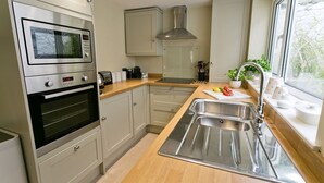 Cocina moderna con horno integrado, pileta de acero inoxidable y ventana que proporciona luz natural.