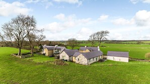 A cluster of stone houses with a grassy field and trees in the background. - Afon Menai -  a hot tub that sleeps 4 guests  in 2 bedrooms (Llanfairpwllgwyngyll)
