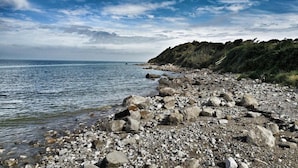 Ein felsiger Strand mit klarem Wasser und einem bewölkten Himmel.