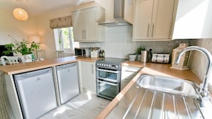 Una cucina moderna con elettrodomestici in acciaio inossidabile, un piano di lavoro in legno e mobili bianchi.