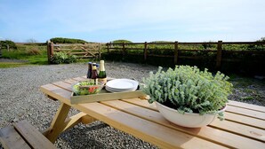 Un tavolo da picnic in legno con insalatiera, piatti e bottiglie di bevande.