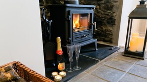 Un rincón acogedor con chimenea de leña, una botella de champán, dos copas y velas.