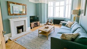 Ein Wohnzimmer mit Kamin, einer Couch, einem Couchtisch und einem Fernseher.