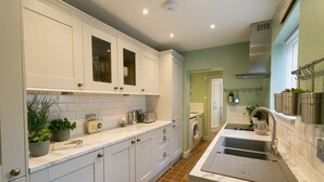A modern kitchen with white cabinets, a built-in oven, and a stainless steel sink. - Hyfrydle -  a coastal that sleeps 6 guests  in 3 bedrooms (Beaumaris)