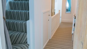 A staircase with striped upholstered steps leading to a landing. - Hyfrydle -  a coastal that sleeps 6 guests  in 3 bedrooms (Beaumaris)